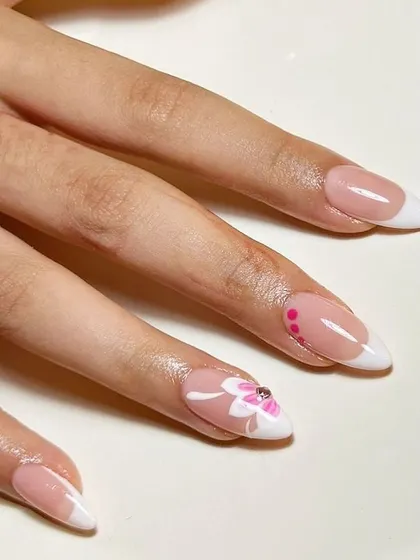 A side view showcasing the elegant almond shape and the delicate floral artwork on this French manicure.