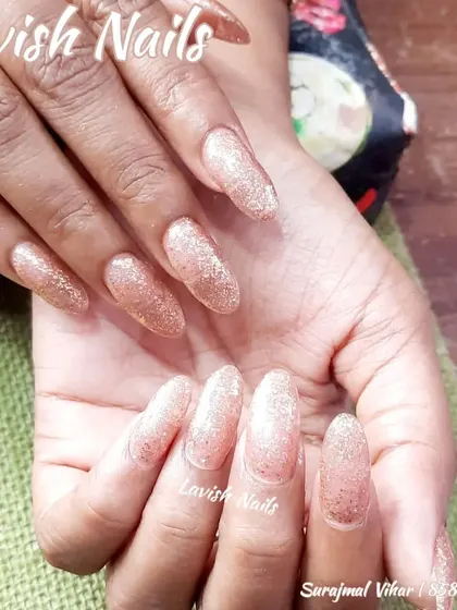 A full set of long, almond-shaped nails with a beautiful rose gold glitter polish, offering a warm and glamorous shimmer.