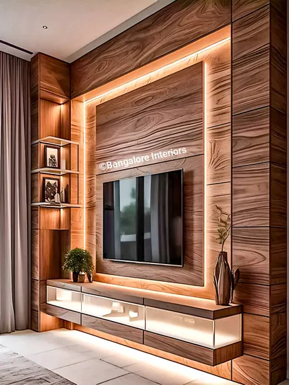 A luxurious TV wall design featuring rich, textured wood panels and a floating glass-front console. The recessed LED lighting frames the TV, making it the clear focal point of the room.