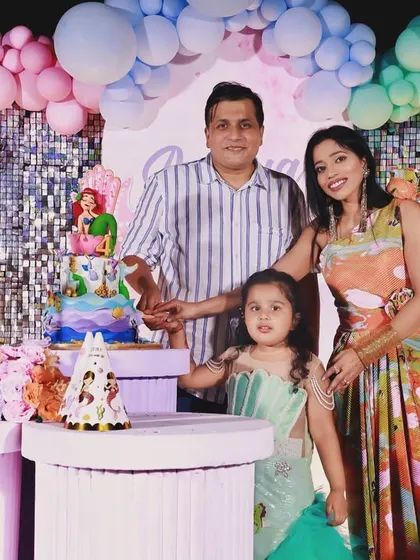 A family portrait at the Little Mermaid-themed party. The colorful decor and character cutouts create a vibrant and festive atmosphere.