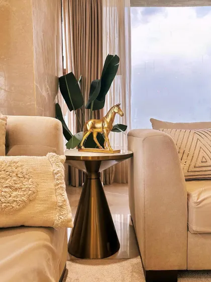 It's never just a corner table. We styled this space with a sleek metallic side table, a golden horse sculpture, and lush greenery to create a small moment of beauty and luxury.