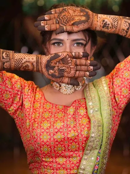 A striking pose that highlights the intricate details of the bridal mehndi on both hands.