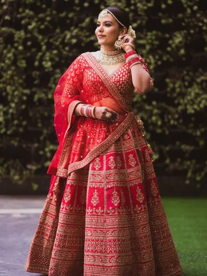 A full-length shot of the bride, showing off her stunning red lehenga. The makeup is elegant and comfortable, allowing her to shine effortlessly.