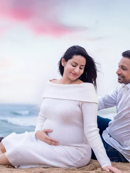 The soft colors of the sky are edited to create a dreamy, pastel backdrop for this romantic couple's portrait on the sand.