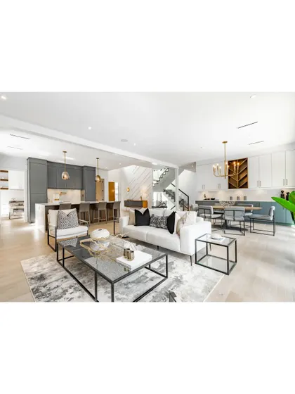 An example of a bright and airy open-concept home. The living, dining, and kitchen areas flow seamlessly into one another, unified by a light wood floor and a clean, contemporary design aesthetic.