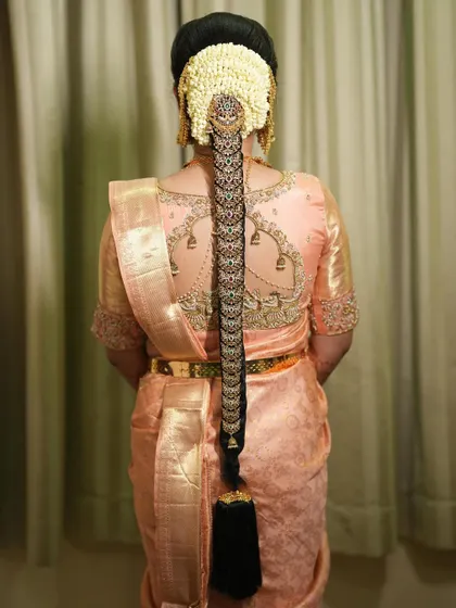 The back of the peach saree blouse is adorned with charming little bell motifs.