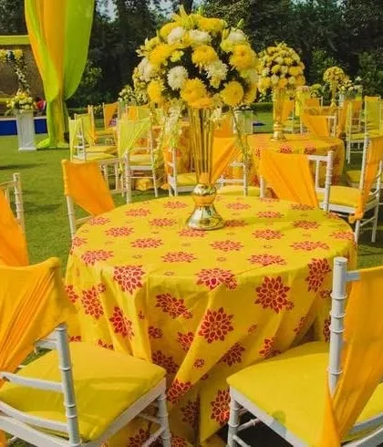 A vibrant table setup for a Haldi lunch. I used printed yellow tablecloths, matching chair drapes, and a tall floral centerpiece to continue the festive theme throughout the dining area.