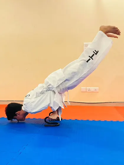 Here, a student performs a challenging push up variation on grips, a drill designed to build exceptional wrist and upper body strength for powerful punches.