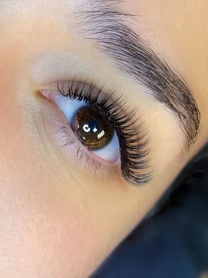 A gorgeous close-up of a client's eye, showing off her new, perfectly applied lash extensions. The sparkle in her eye says it all.
