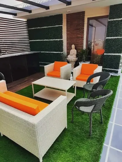 This terrace combines comfortable wicker seating with vertical garden walls and a Buddha statue, creating a space that is both stylish and serene.