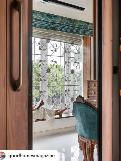 A peek through the doors of the master suite in 'Mina Nivas', showing the ornate window grill and the vintage-style vanity. This home is all about blending traditional details with modern comfort.