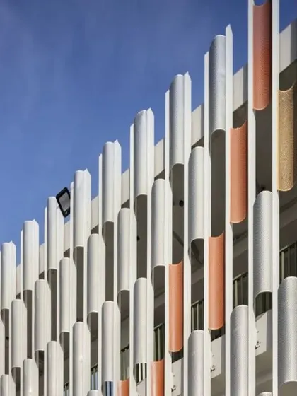 A detail of the colorful, perforated facade of the SPS Clinic. The design is both functional, mitigating heat and glare, and expressive, contributing to the clinic's unique architectural identity.