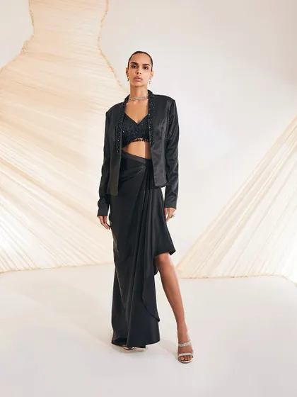 The Debro Jacket Set is an alluring amalgamation of urban design and Indian adornments, featuring a rich satin blazer with a draped skirt.