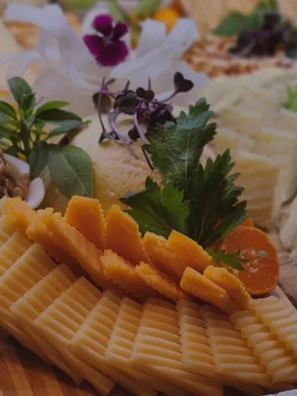 A detailed shot of intricately sliced cheeses, garnished with fresh herbs and edible flowers. This highlights the meticulous attention to detail that goes into the presentation of every board.