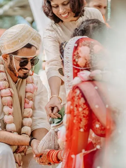A creative, blurry shot of a wedding ritual, focusing on the couple's hands and the sacred objects.
