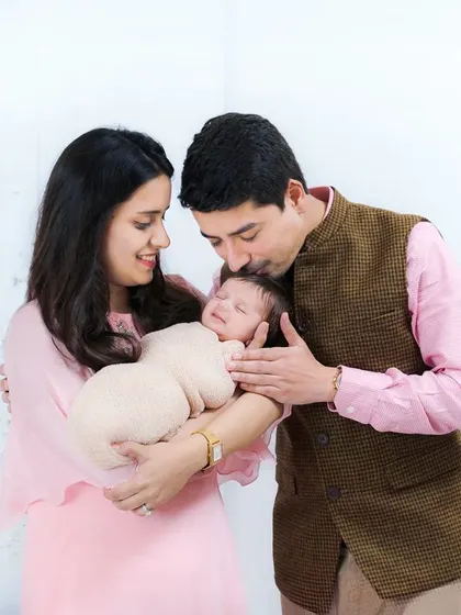 A beautiful family moment as a father kisses his newborn's head while the mother holds the baby. A portrait filled with warmth and affection.