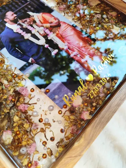 A detailed close-up of the names and date on the wooden frame, showing the delicate gold lettering over the preserved flowers.
