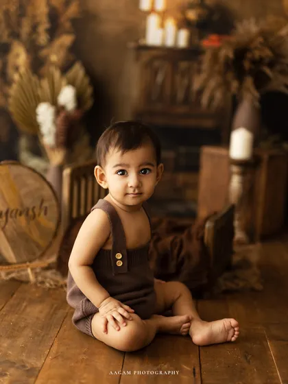 A handsome portrait of a one-year-old boy sitting proudly next to his personalized nameplate. A wonderful way to commemorate his first birthday.