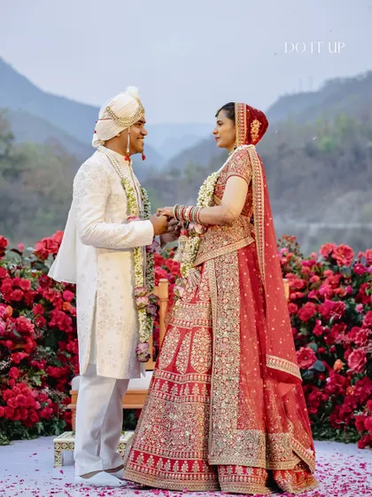 A beautiful portrait of the couple, framed by the sea of red roses. The traditional attire and the classic floral choice create a timeless and soulful image.