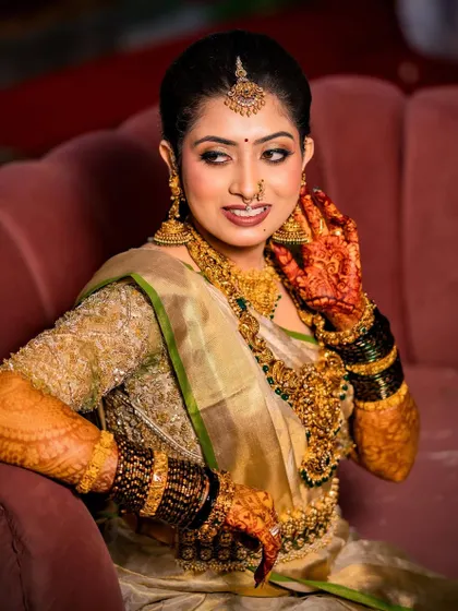 This bride looks absolutely breathtaking in her gold Kanchivaram saree. The custom blouse is heavily embroidered, adding to the richness of her traditional bridal look.