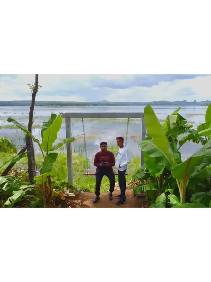Two friends relaxing on our lakeside swing, surrounded by lush banana plants. It's one of the many photo-worthy spots at our resort.