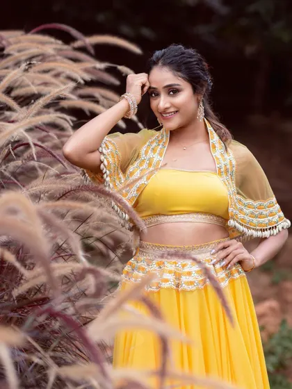 A lovely outdoor shot of the model in the yellow lehenga, with the detailed embroidery on the capelet in focus.