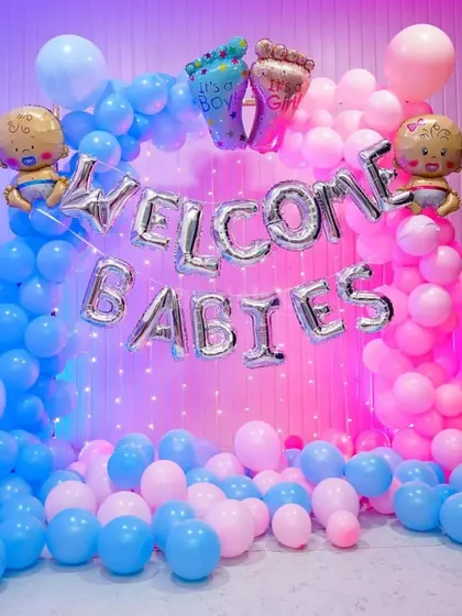 A 'Welcome Babies' decoration for twins, with a pink and blue balloon arch and fairy lights.