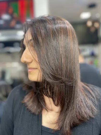 A simple and elegant layered cut on medium-length dark hair, styled straight for a polished finish.