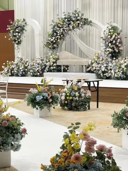 A pastel-themed stage with a mix of colorful flowers, ideal for a daytime engagement or reception.