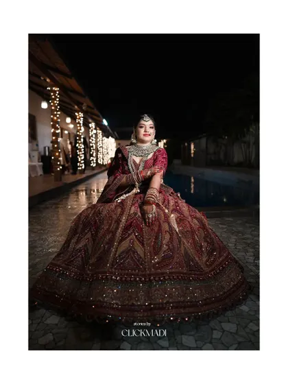 A regal bridal portrait taken at night, with the bride's elaborate lehenga spread out around her, creating a majestic image.