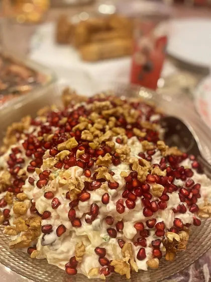 A bowl of my refreshing Russian Salad, generously topped with crunchy walnuts and bright red pomegranate seeds.