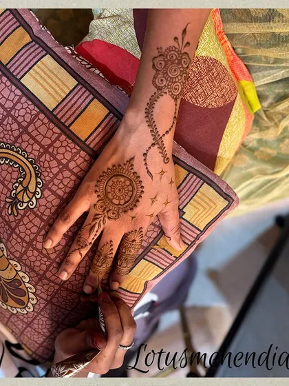 A simple and chic design featuring a mandala on the palm and a trailing pattern on the wrist. It's a modern take on traditional mehendi.