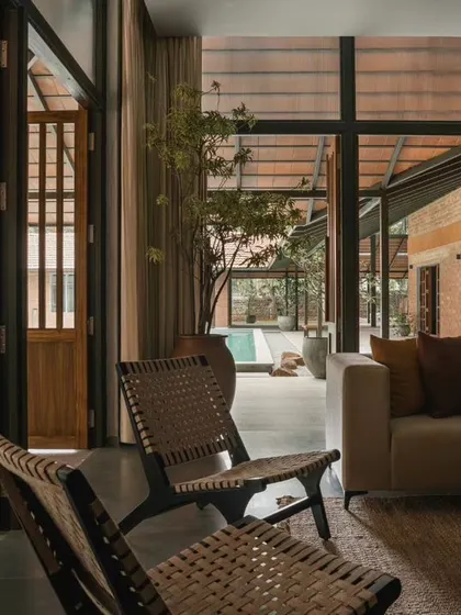 Custom-designed wooden screens and woven chairs add texture and warmth to the living area. The space is designed to be a comfortable, modern lounge that still feels connected to the rustic farmhouse aesthetic.