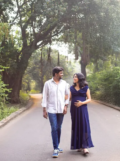 A candid walking shot of the couple on a quiet, tree-covered road, capturing a natural and romantic moment.