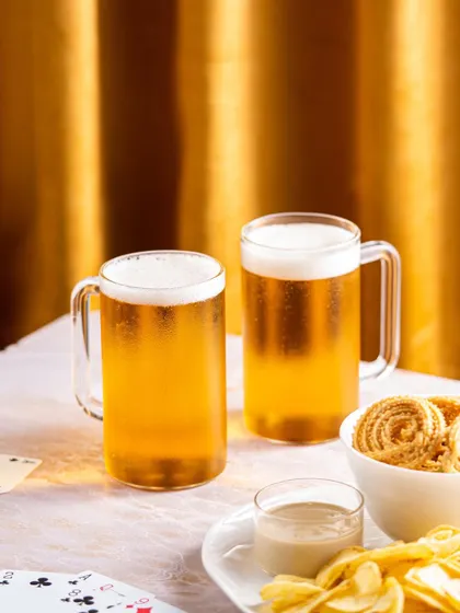 Product photography for Borosil beer mugs, styled for a festive or party setting with cards and snacks.