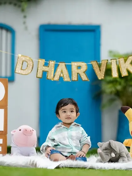 A cute outdoor first birthday setup with 'ONE' blocks and the birthday boy's favorite cartoon characters.