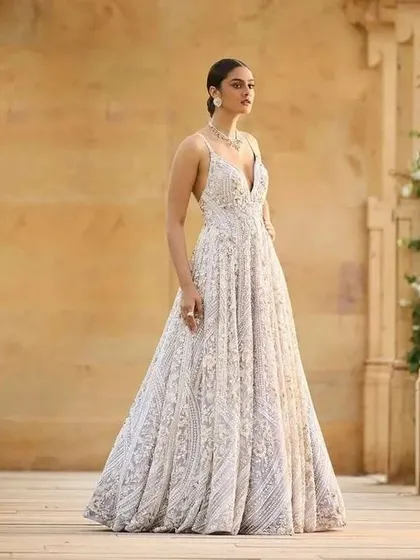This fully embroidered white gown is a showstopper. The plunging neckline and flowing A-line silhouette create a look that is both glamorous and sophisticated, perfect for a reception or cocktail party.