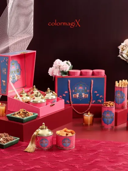 A detailed view of our pink and blue themed Diwali hamper. The set includes decorative jars with golden lids, scented candles, and assorted snacks, combining traditional motifs with contemporary colors.