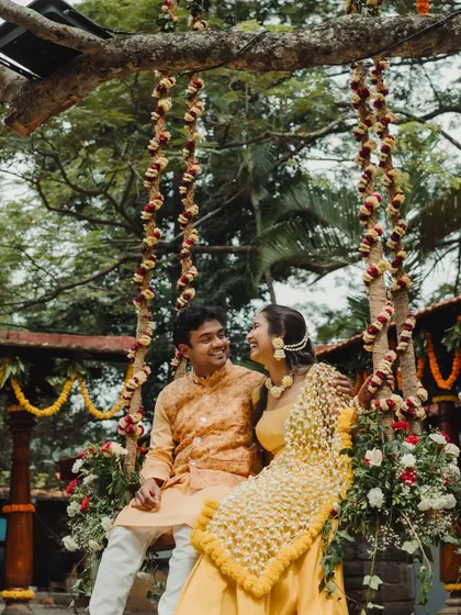 A happy couple sharing a moment on a beautifully decorated floral swing, a classic and romantic element for any Mehendi or Haldi.