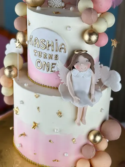 Turning one never looked so sweet. This angelic first birthday cake features soft pink and white ombre, fluffy clouds, and a sparkling number one topper for a heavenly celebration.