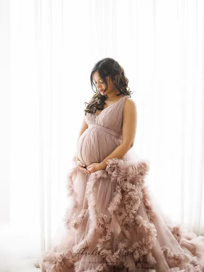 A soft and dreamy portrait by the window, with the mother-to-be in a mauve ruffled gown, bathed in natural light.