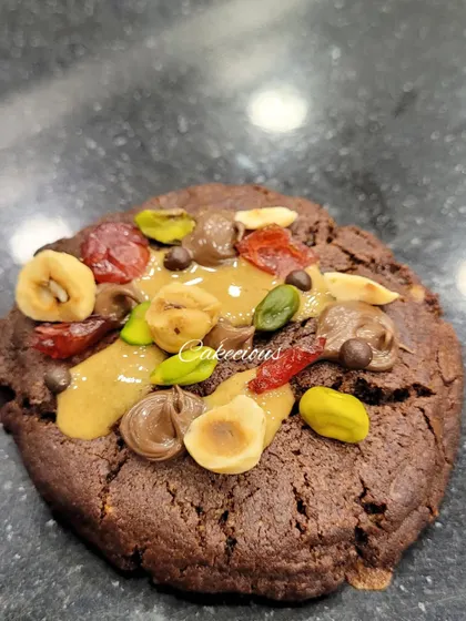 A close-up of my dark chocolate overload cookie. It's packed with nuts, dried fruit, and chocolate chunks for a truly decadent treat.