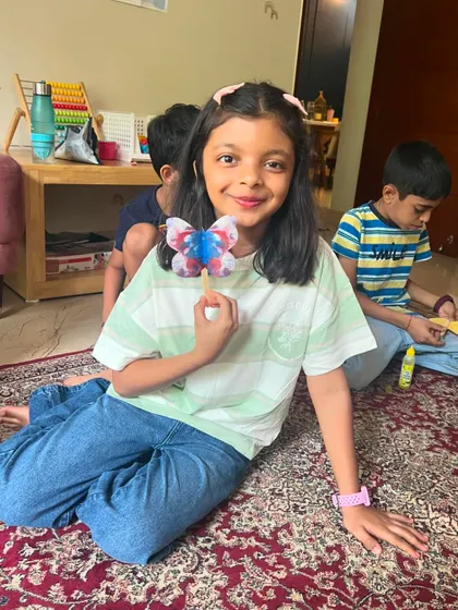 A proud smile from a young artist with her colorful butterfly craft.