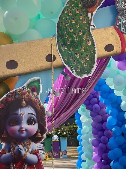 A close-up of the Krishna-themed entrance arch, showing the detailed cutouts of Little Krishna and a large flute prop.