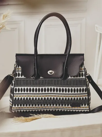 A beautifully styled shot of a patterned handbag on a table with dried pampas grass. This creates a bohemian, chic aesthetic that elevates the product.