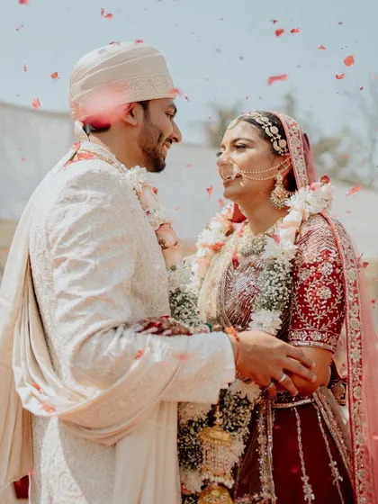 A classic varmala moment, filled with smiles and a shower of petals. This shot perfectly captures the joy and tradition of the wedding ceremony.