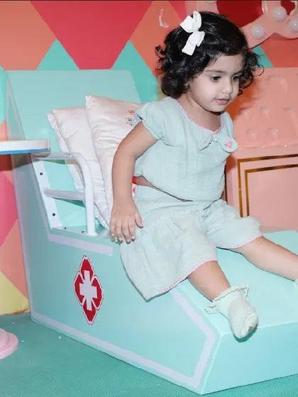 A toddler sits on a cute ambulance-themed chair in our pretend-play hospital.