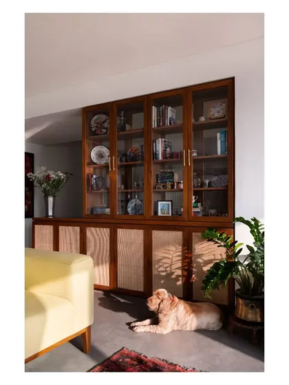 A custom teak and rattan crockery unit, perfectly sunlit and watched over by the home's most relaxed resident.