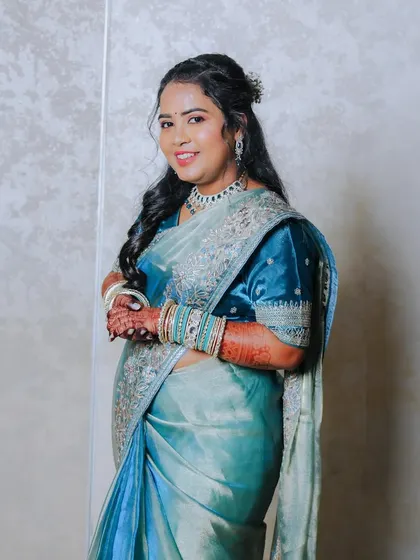 An elegant three-quarter portrait of the bride in her beautiful blue saree. She smiles gently at the camera, looking poised and happy during her reception.