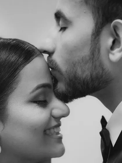 An intimate black and white close-up of a forehead kiss. This tender moment from a reception captures the deep affection between the couple.